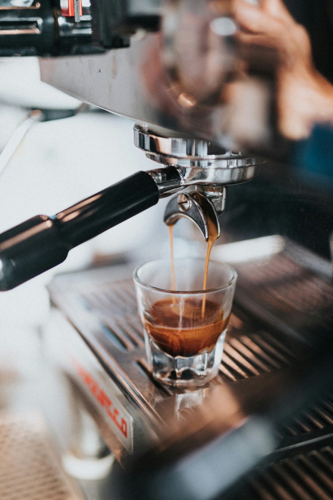 Zwei Espressostrahlen laufen aus dem Siebträger in ein kleines Glas, darin bildet sich die Crema